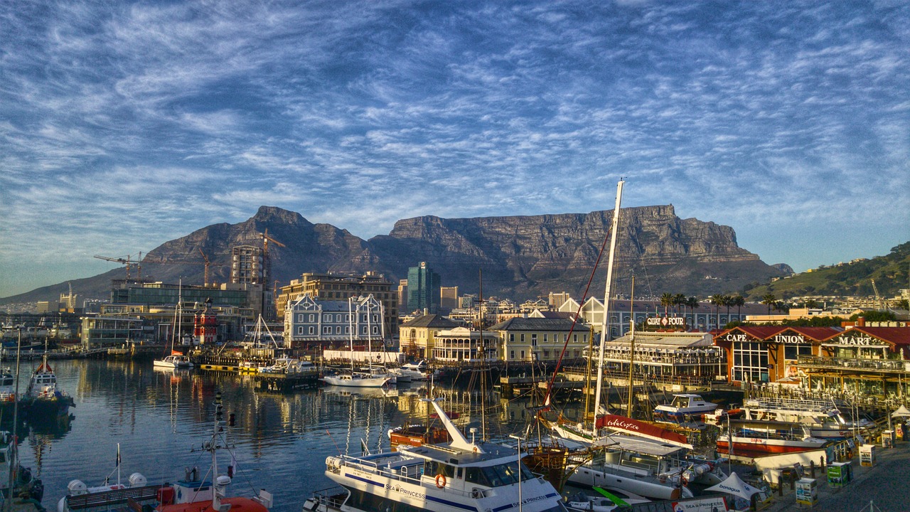 Harbour boats in a waterfront setting with a high flat mountain and blue sky in the background